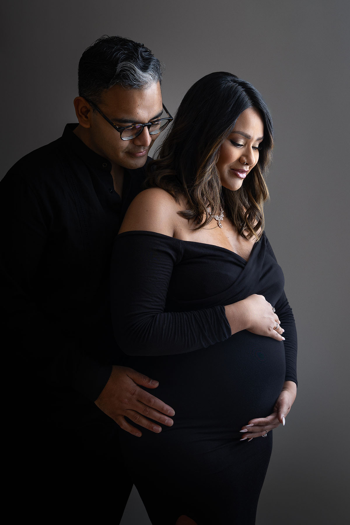 couple iin studio posed with maternity dress moody