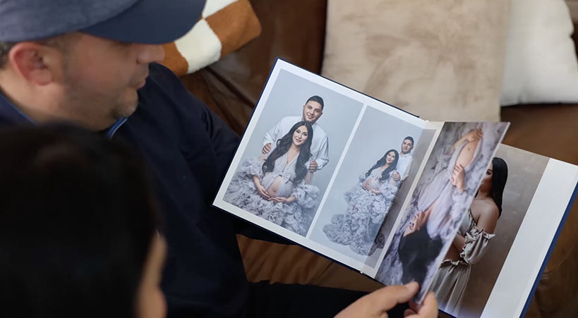 couple looking at their maternity photo album in San Diego