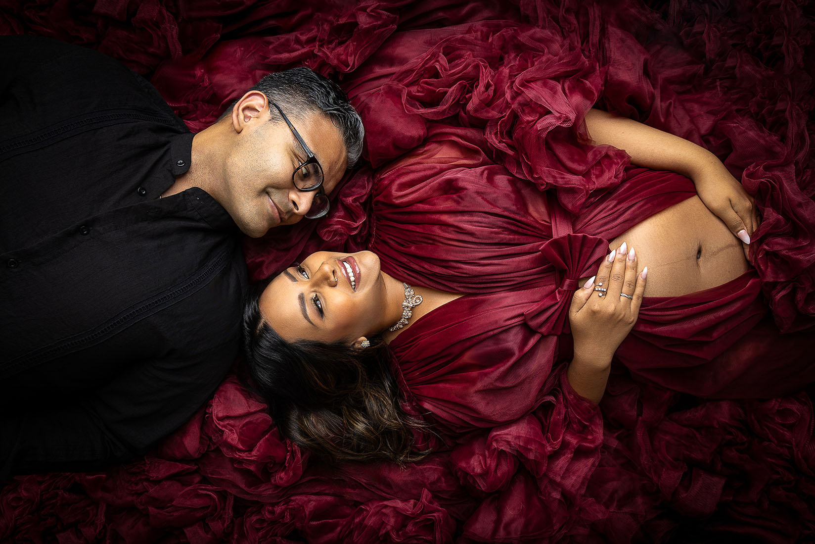 couple surrounded by dress with dramatic lighting